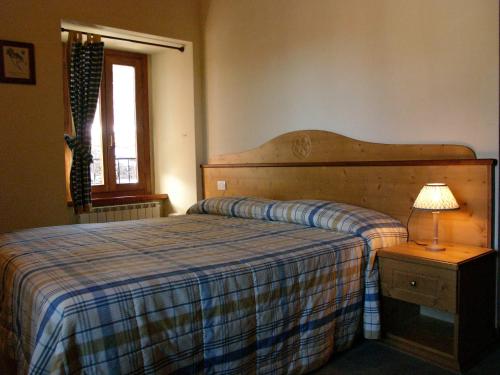 DumenzaRifugio Campiglio的一间卧室配有一张床和一张带台灯的桌子