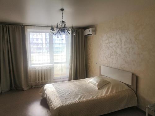 布拉戈维申斯克1 комнатная квартира的一间卧室设有一张床和一个大窗户