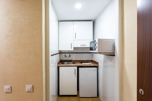 塞维利亚莱斯特尔公寓的小厨房配有白色橱柜和微波炉