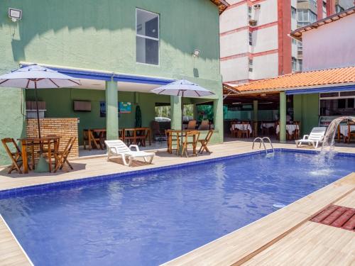 福塔莱萨Pousada Arco Iris Fortaleza的一个带桌椅和遮阳伞的游泳池