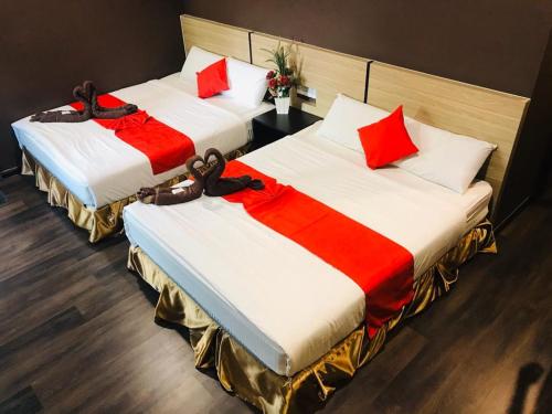 怡保Highway Times Inn Hotel的两张带红色和白色枕头的床