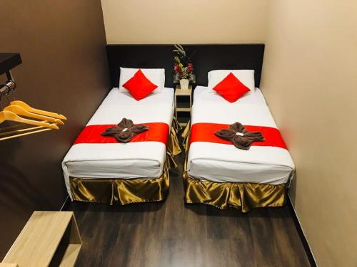 怡保Highway Times Inn Hotel的宿舍间内的两张床,配有红色枕头
