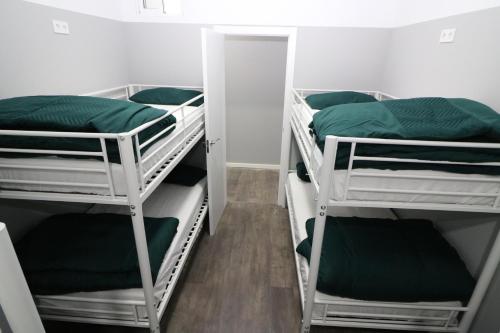 马德里Madrid Downtown Hostel的客房设有三张双层床,配有绿色床单