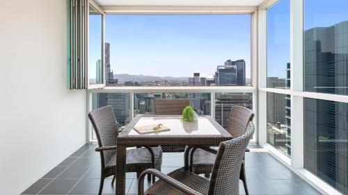 布里斯班Oaks Brisbane Festival Suites的阳台配有桌椅和大窗户。