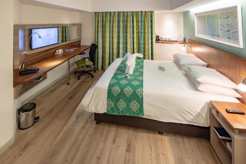 德班City Lodge Hotel Durban的酒店客房配有一张床、一张书桌和一台电脑