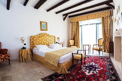 佩兹迪格雷科马塞里亚瑞莱斯卡尔迪纳莱酒店的一间卧室设有一张大床和一个壁炉