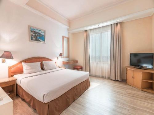 雅加达Hotel Bulevar Tanjung Duren Jakarta的配有一张床和一台平面电视的酒店客房