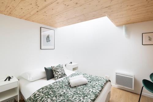 雷恩LA DEROBEE - Havre de paix en ville的一间卧室设有一张床和木制天花板