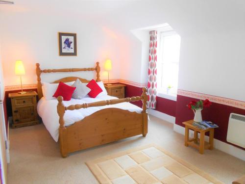 金尤西The Osprey Hotel的一间卧室配有一张带红色枕头的木床。