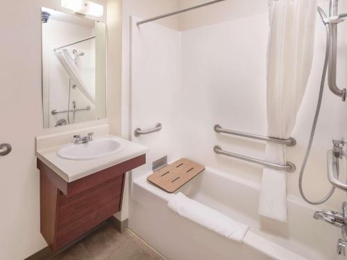 梅里尔维尔WoodSpring Suites Merrillville的白色的浴室设有水槽和淋浴。