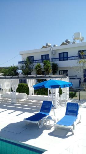普罗塔拉斯弗罗卡斯公寓酒店的游泳池畔的2把蓝色椅子和遮阳伞