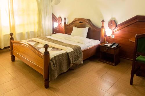 姆巴拉拉Palm world Hotels Mbarara的一间卧室配有一张大床和木制床头板
