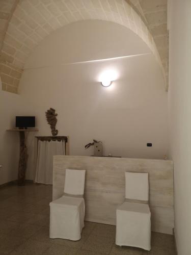 卡萨拉诺B&B Corte San Giuseppe的白色的客房配有两张白色椅子和一张桌子