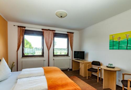 SchmogrowPension zum Reiterhof的一间卧室配有一张床、一张书桌和两个窗户。