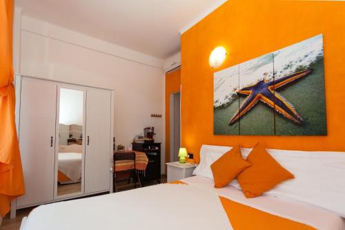 卡莫利斯特拉海滨酒店的一间卧室配有橙色墙壁、一张床和镜子