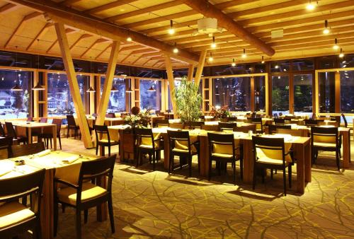 亚霍里纳加哈利纳特玛酒店的餐厅设有木桌、椅子和窗户。
