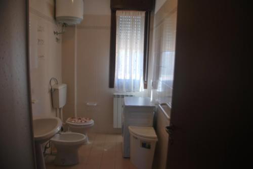 罗索利纳马雷Acquasmeralda appartamento 01的浴室设有2个卫生间、水槽和窗户。
