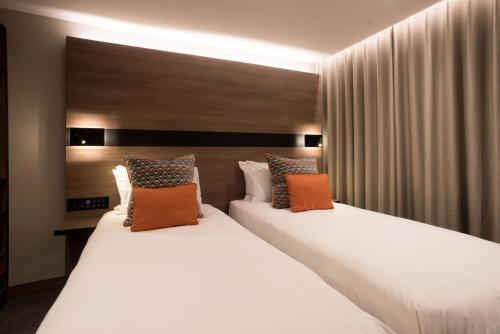 伦敦牛津酒店的配有2张床铺的酒店客房,提供白色和橙色枕头