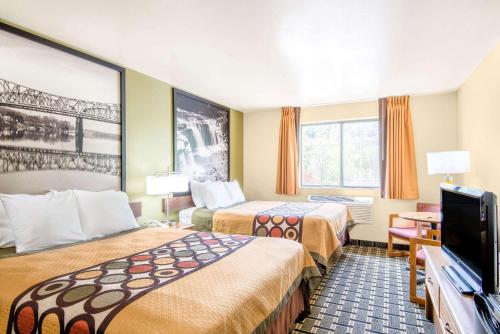惠灵Super 8 by Wyndham Wheeling Saint Clairsville OH Area的酒店客房设有两张床和一台平面电视。