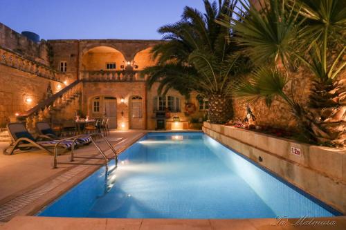 阿尔卜Ta' Matmura Farmhouse的庭院内的游泳池,有房子
