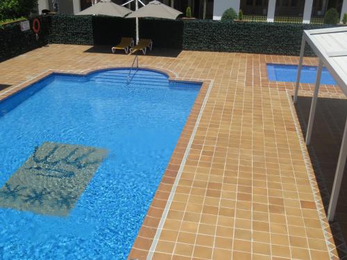 埃斯塔蒂特圣安娜酒店的一座带瓷砖地板和遮阳伞的大型游泳池