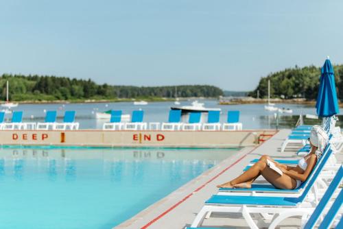 Sebasco Estates希巴斯科港度假酒店的躺在游泳池旁椅子上的女人