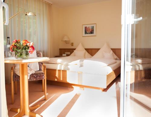 巴登韦勒摩格索娜酒店的酒店客房,设有两张床和一张鲜花桌。