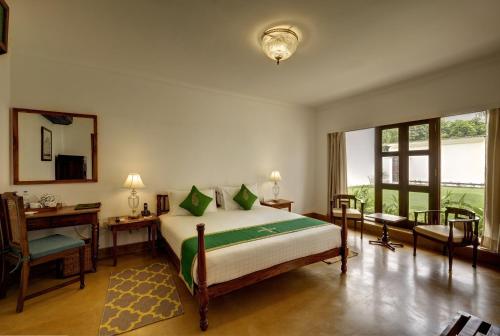 勒克瑙Saraca Hotel Lucknow的一间卧室配有一张床、一张书桌和一面镜子