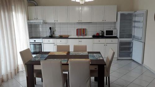 尼亚普拉莫斯Stathoris Deluxe Apartment的一间带桌椅的厨房和一间带白色橱柜的厨房