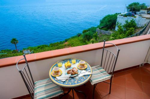 普莱伊亚诺利曼尼花园公寓式酒店的阳台上的一张桌子和一盘食物,俯瞰着水面