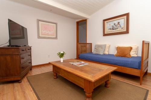 彼得罗波利斯Suites Caipira Vale das Videiras的客厅配有床和茶几