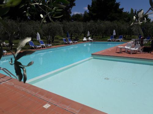 蒙特普齐亚诺Villa Nottola的一个带椅子和椅子的大型蓝色游泳池
