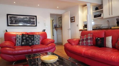 特维德上游的贝里克米尔码头公寓的客厅配有两张红色皮革沙发和一张桌子