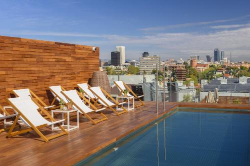 马德里梅利亚马德里塞拉诺酒店的屋顶上一组躺椅,带有游泳池
