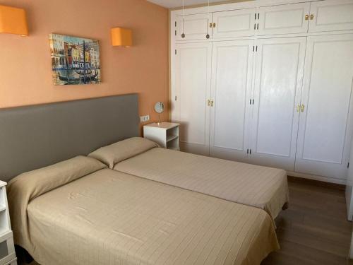 多列毛利诺斯Apartamentos SOL y PLAYA Torremolinos的一间卧室配有一张床和白色橱柜