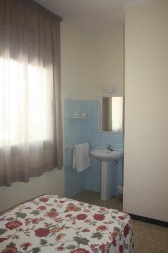 萨洛托雷玛尔旅馆的一间卧室配有床、水槽和镜子
