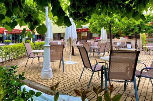 昆卡托雷曼加纳酒店的一个带桌椅和白色遮阳伞的庭院。