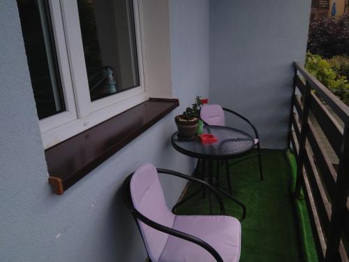 露米雅Pokoje Gościnne Bajka的阳台配有小桌子和椅子,设有窗户