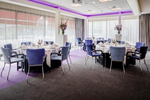 埃因霍温Holiday Inn Eindhoven Centre, an IHG Hotel的宴会厅配有桌椅和紫色照明