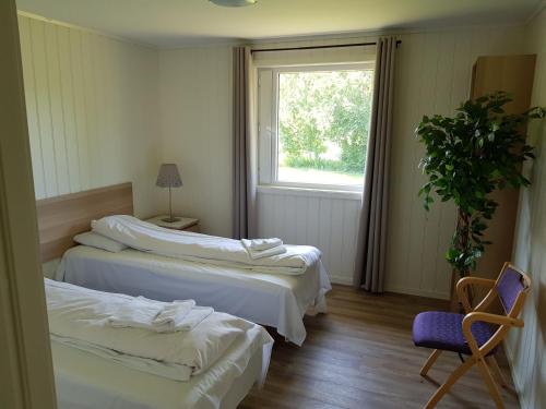摩城Bech's Hotell & Camping的客房设有两张床、一把椅子和窗户。