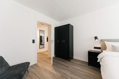西蒙斯瓦尔德Moderne 3 Zi-FeWo "Industrial Style" 70 qm Naehe Freiburg的卧室配有黑橱柜,位于床边