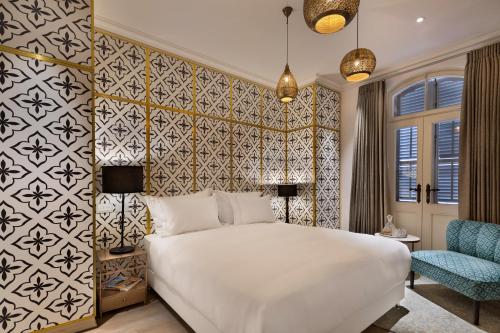 特拉维夫The Drisco Hotel Tel Aviv - Relais & Châteaux的卧室配有白色的床和蓝色椅子