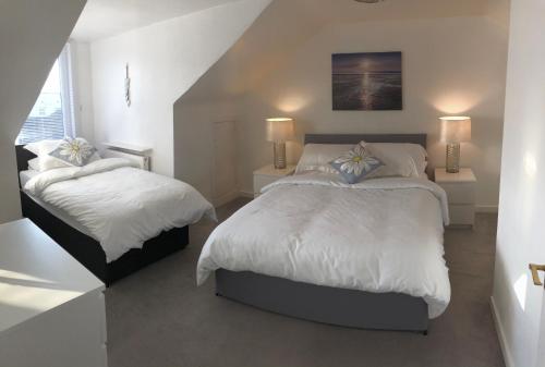 阿德罗森Arran Ferry Apartment的一间白色卧室,配有两张床和楼梯