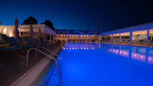 普托莱迈达潘特里迪斯酒店的夜间游泳池,配有桌椅