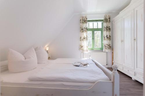 欧巴德伍斯图Ferienhaussiedlung Strandperlen Sanddornhof 3c (Typ II)的窗户客房内的一张白色床