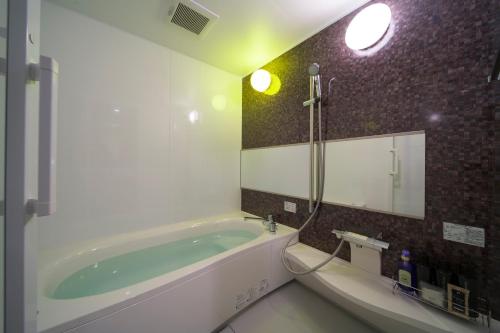 和歌山HOTEL LASCALA的带浴缸和镜子的浴室