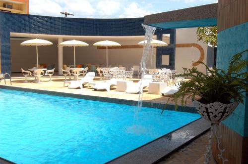 圣路易斯普拉亚蓬德黑沙酒店的一个带椅子和遮阳伞的游泳池和一个喷泉