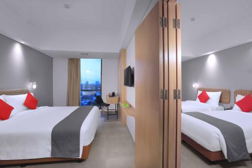 雅加达Neo Hotel Puri Indah的酒店客房设有两张床和电视。