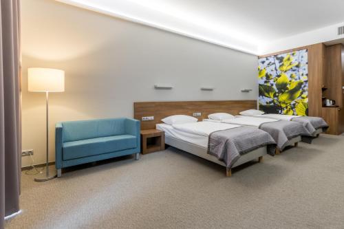 多布龙Kolumna Park Hotel的一间设有两张床和一张蓝色椅子的房间