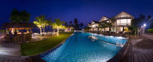 米瑞莎Sri Sharavi Beach Villas & Spa - with 43 metre saltwater infinity pool的夜间在度假村前的游泳池